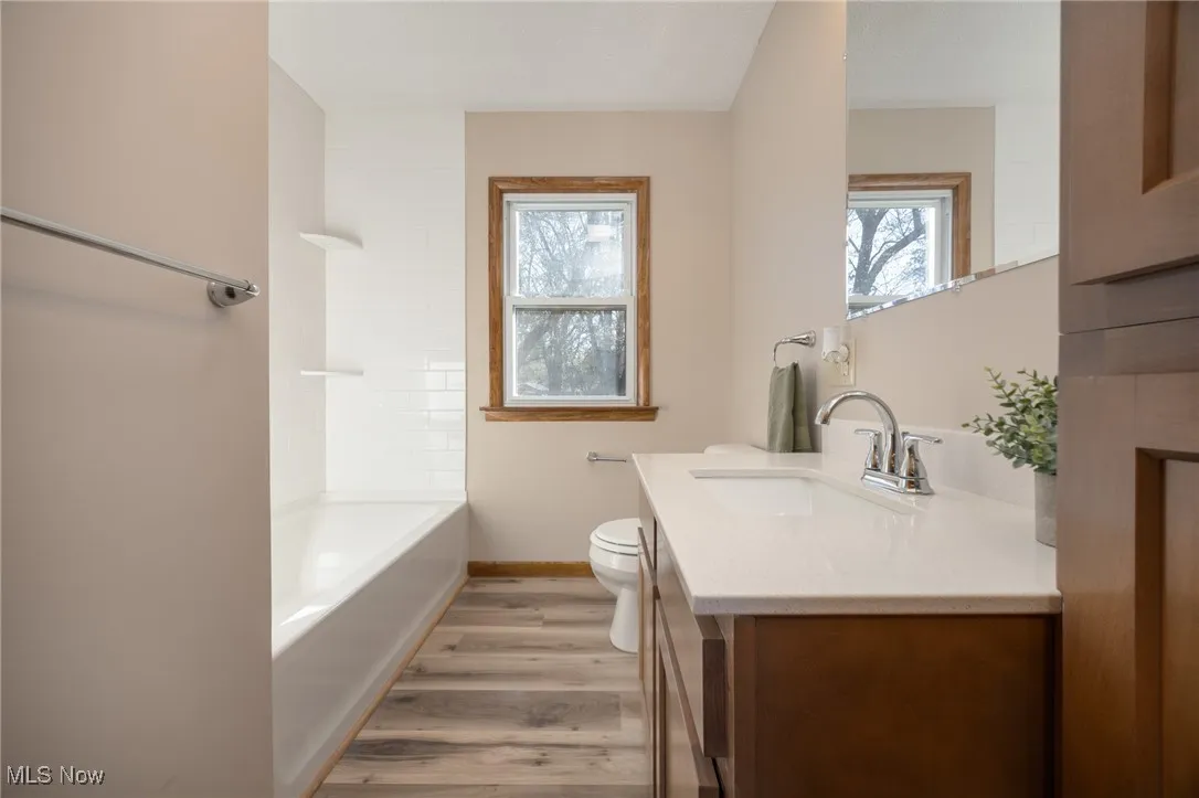Full bath featuring toilet, vanity, wood look LVP floors, and baseboards