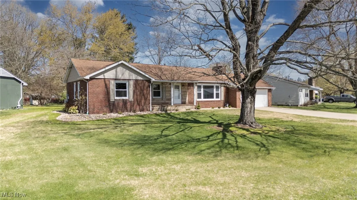Ranch-style house with brick siding, an attached garage, a front yard, and concrete driveway