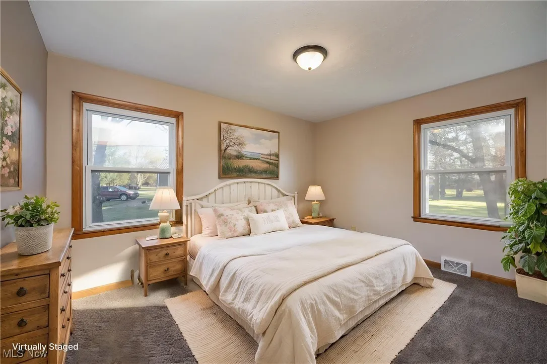 Virtually staged bedroom featuring visible vents, carpet flooring, baseboards, and multiple windows