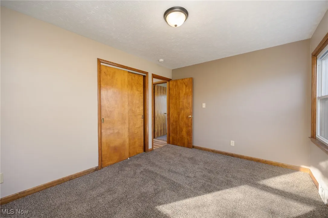 Unfurnished bedroom with baseboards, carpet, and a closet