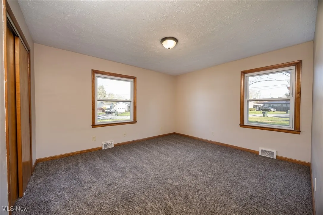 Unfurnished bedroom with visible vents, carpet floors, and multiple windows