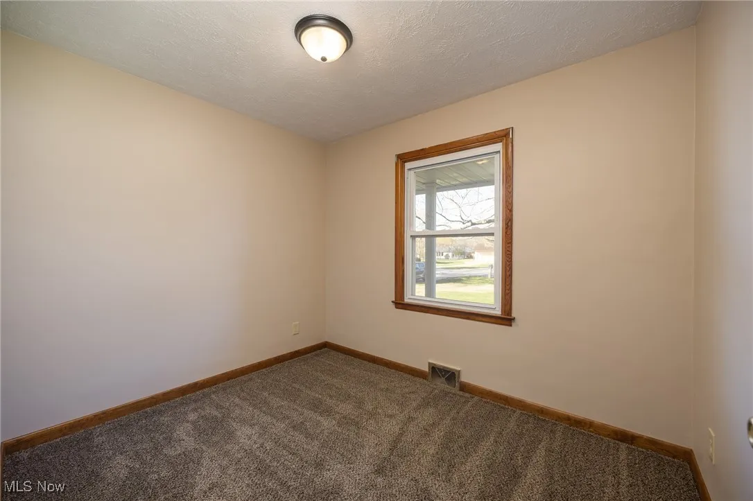 Carpeted bedroom featuring baseboards, a textured ceiling, and visible vents