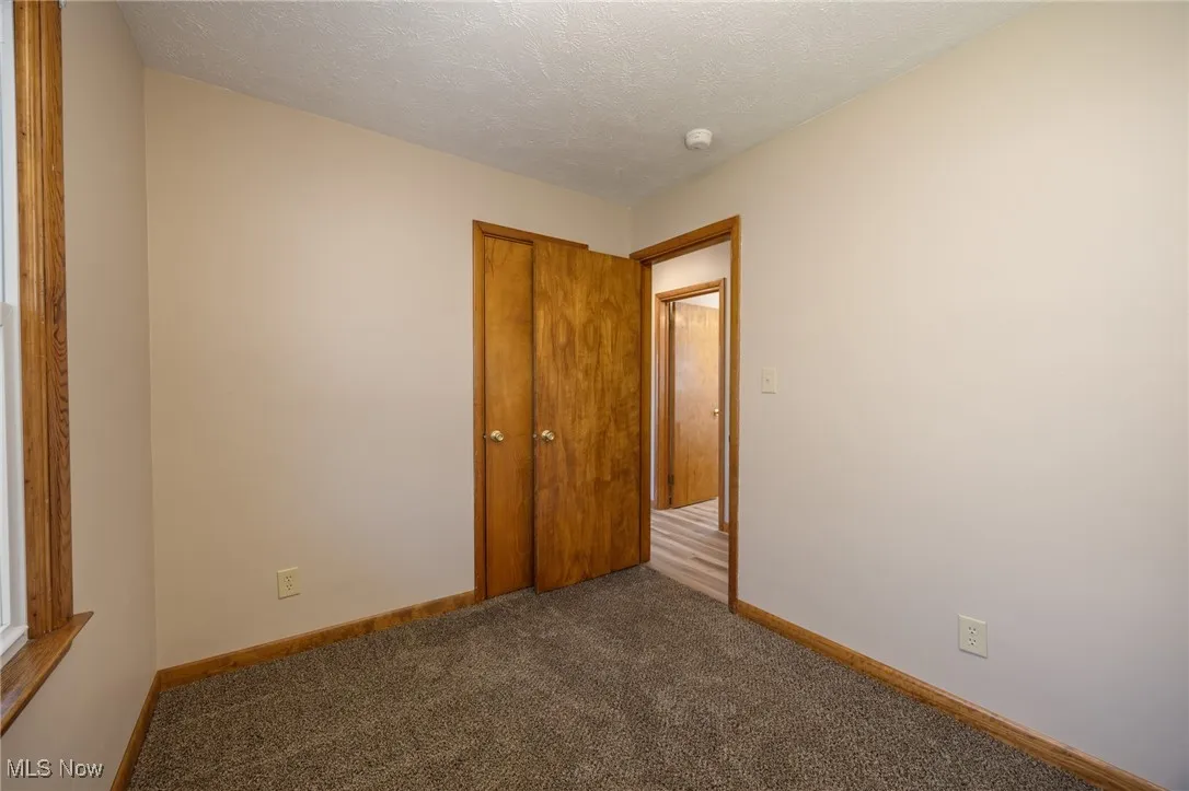 Carpeted bedroom with baseboards and a textured ceiling