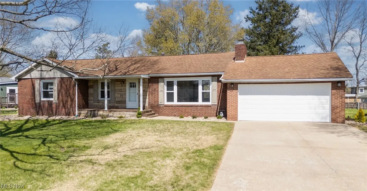 Single story home with concrete driveway, a front lawn, brick siding, and a garage