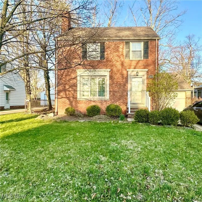 View of front of property with fence, a front lawn, brick siding, and a chimney