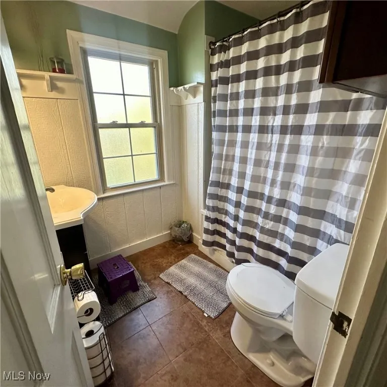 Full bath featuring tile patterned floors, curtained shower, toilet, and vanity
