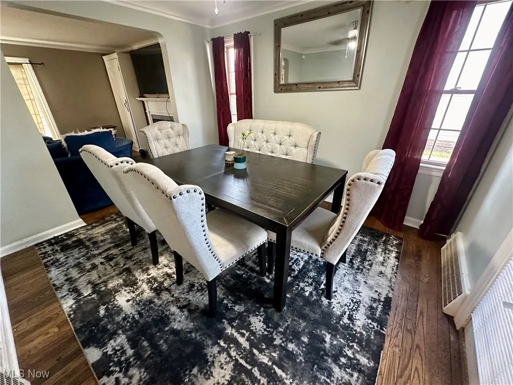 Dining area with baseboards, wood finished floors, ornamental molding, and arched walkways