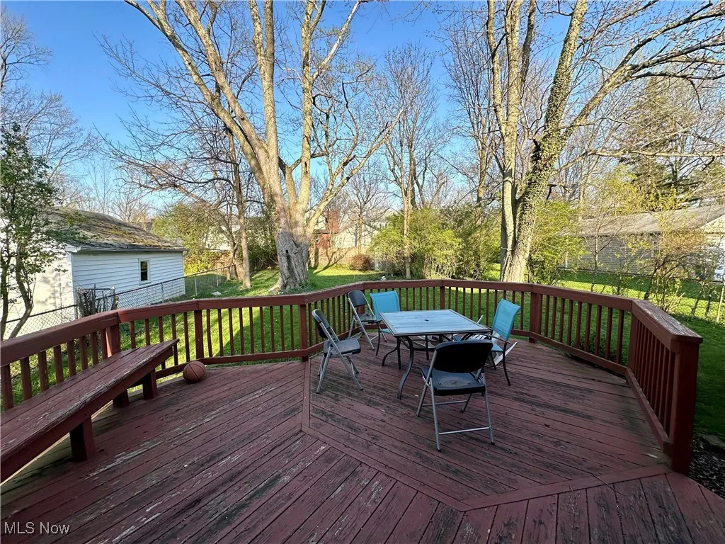 Wooden deck featuring a lawn, outdoor dining area, and fence