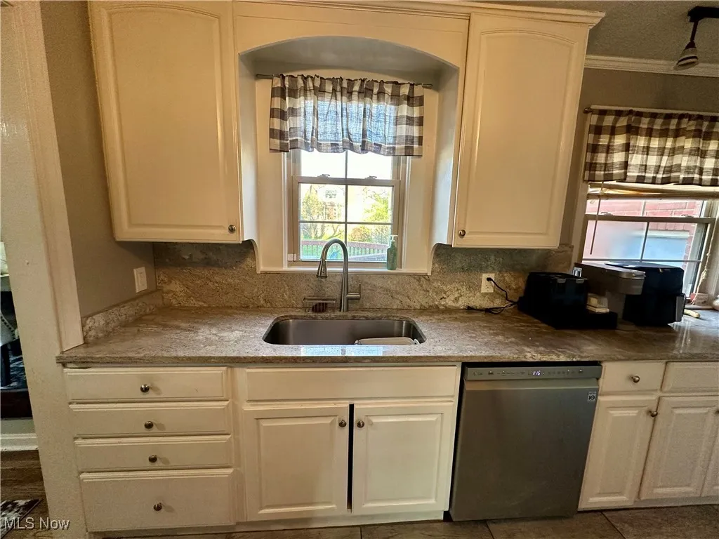 Kitchen featuring white cabinetry, a healthy amount of sunlight, stainless steel dishwasher, and a sink