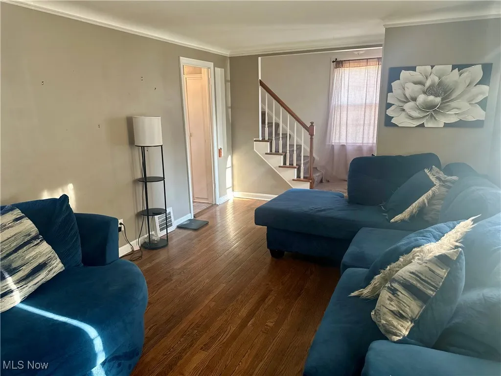 Living room featuring ornamental molding, stairway, wood finished floors, and baseboards