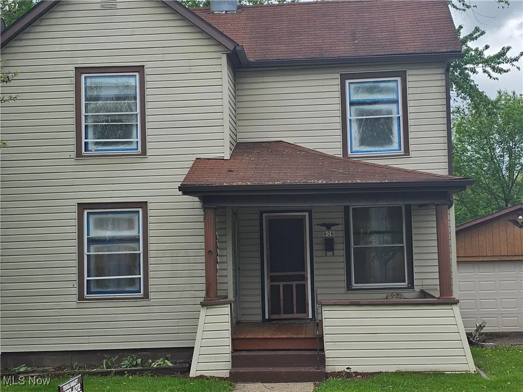 View of front facade with a chimney, roof with shingles, and an outdoor structure