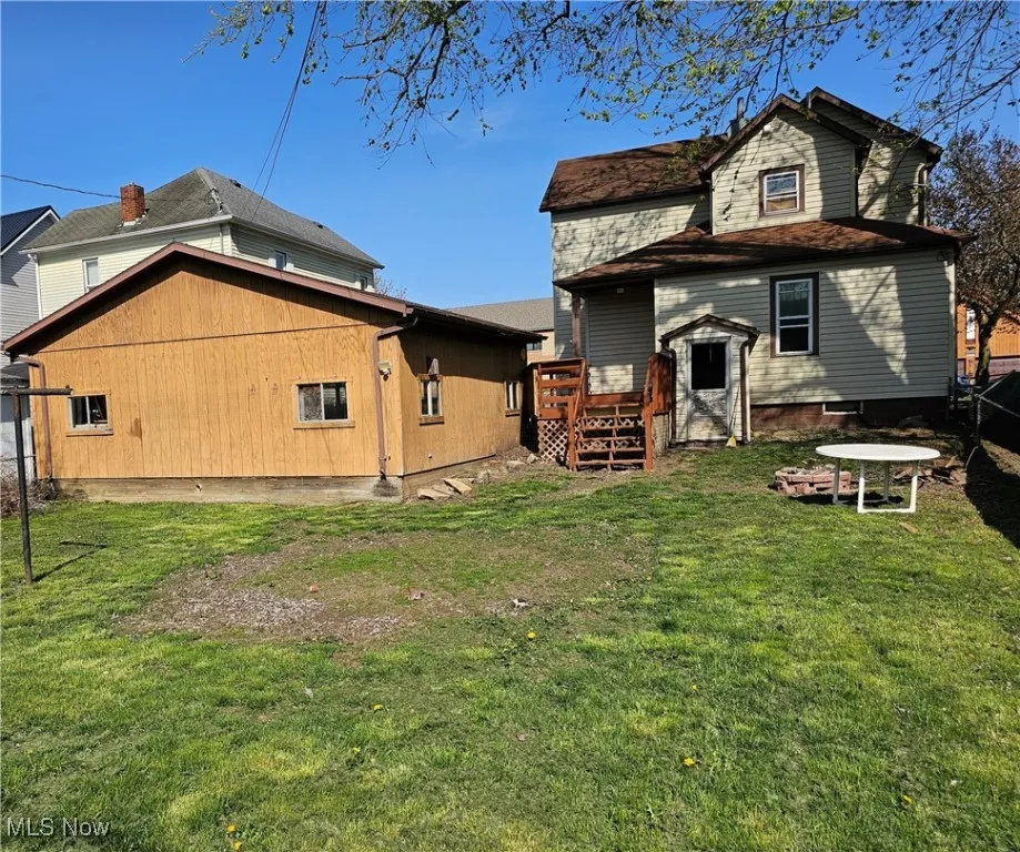 Rear view of property with a wooden deck, a yard, and fence