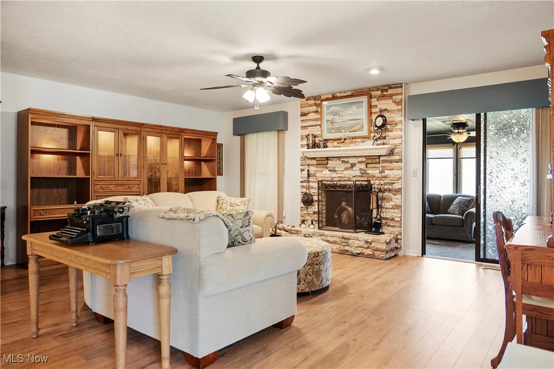 Living area featuring ceiling fan, light wood finished floors, and a fireplace