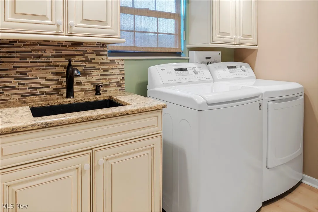 Laundry area with washing machine and dryer, a sink, and cabinet space