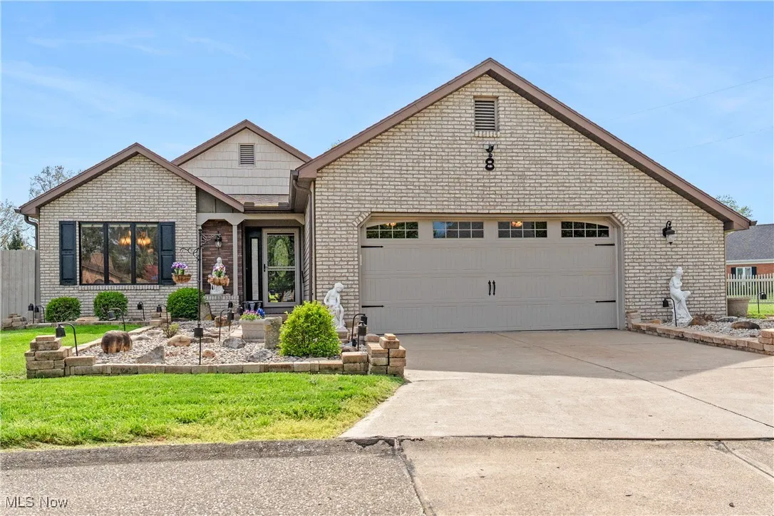 View of front facade with brick siding, an attached garage, driveway, and a front yard