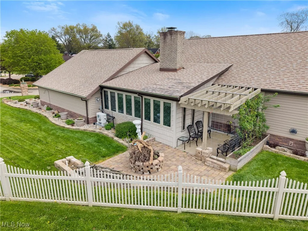 Rear view of house featuring a chimney, an outdoor fire pit, a shingled roof, a yard, and a patio