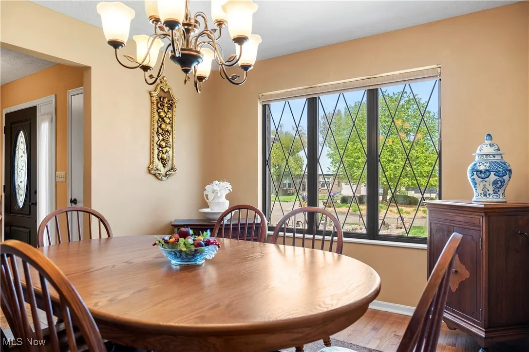 Dining room with a chandelier, wood finished floors, and baseboards