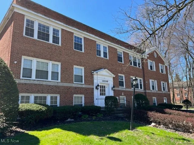 Townhome / multi-family property with a front lawn and brick siding