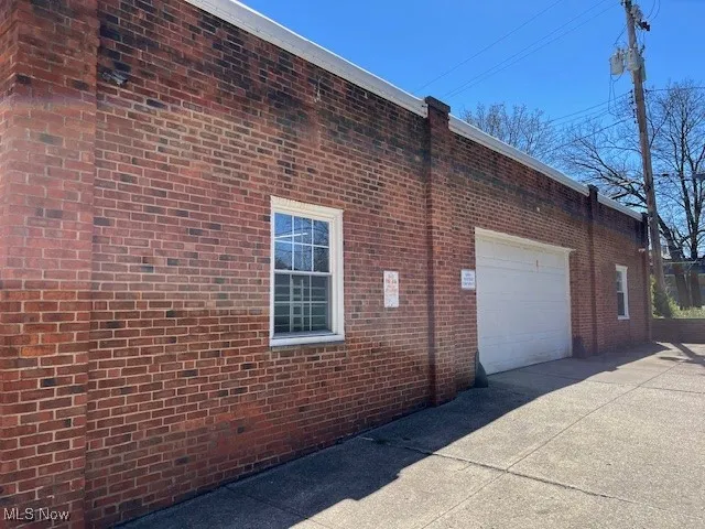 View of side of property with a garage, brick siding, and concrete driveway