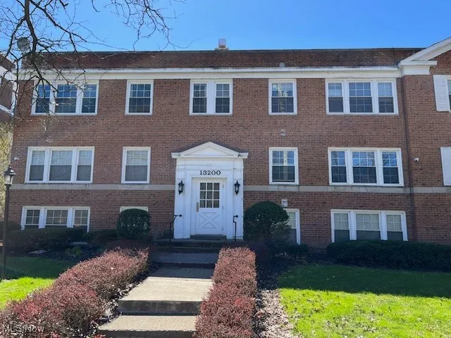 View of property with brick siding and a front yard