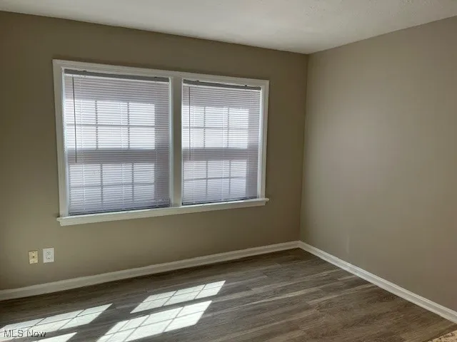 Spare room featuring baseboards and dark wood-style flooring