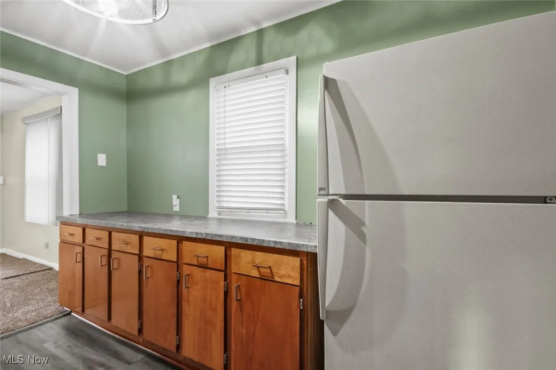 Kitchen with freestanding refrigerator, brown cabinets, plenty of natural light, and light countertops