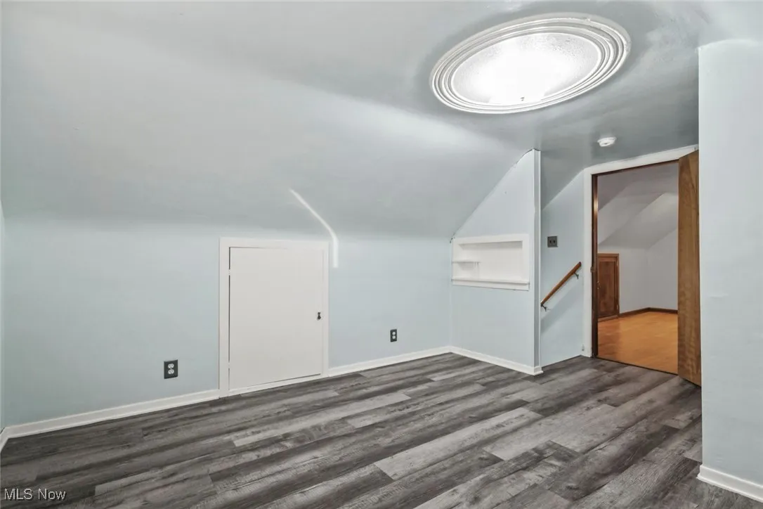 Additional living space with dark wood-style flooring and lofted ceiling