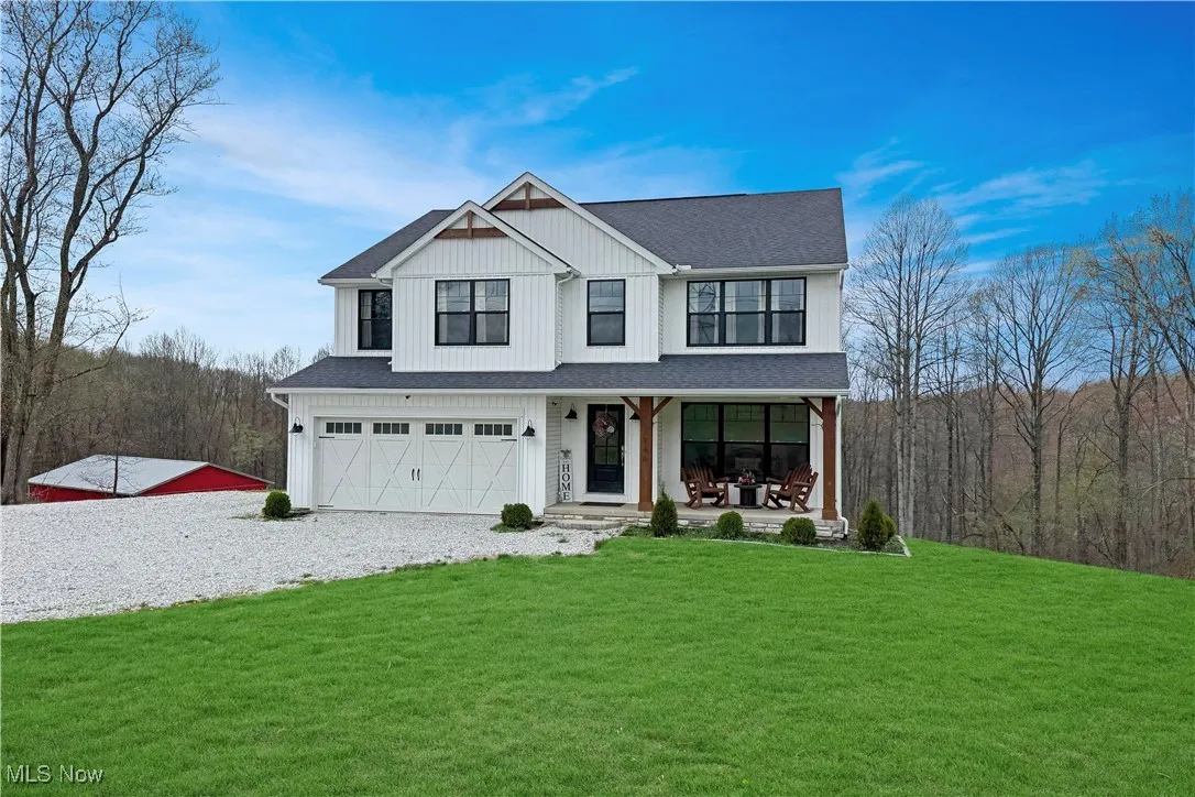 View of front of property featuring roof with shingles, a porch, an attached garage, gravel driveway, and a front yard