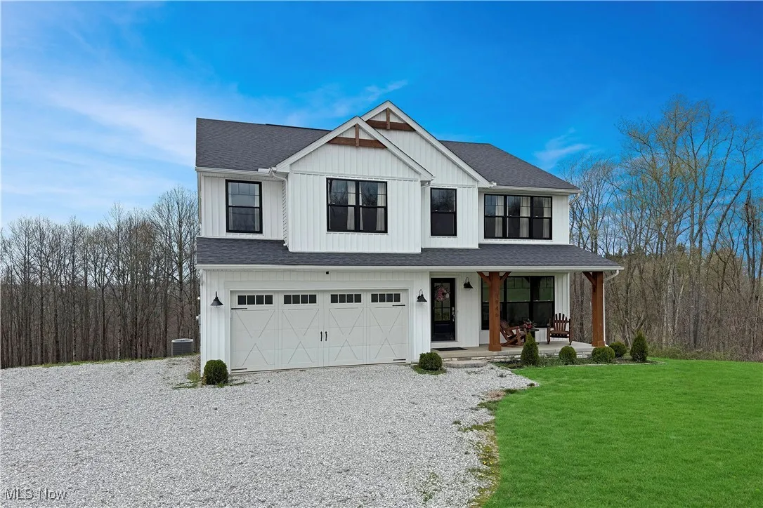 View of front of house with a front lawn, driveway, a porch, roof with shingles, and a garage