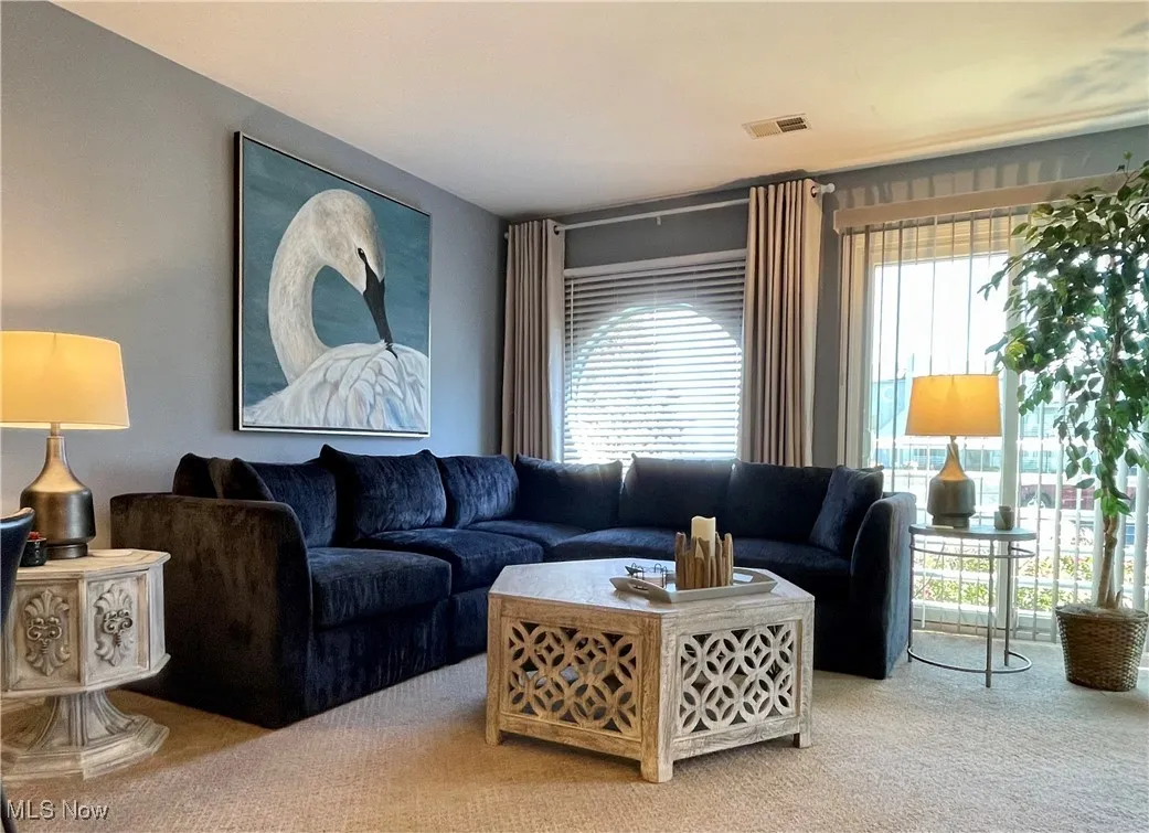 Living room with carpet, visible vents, and plenty of natural light