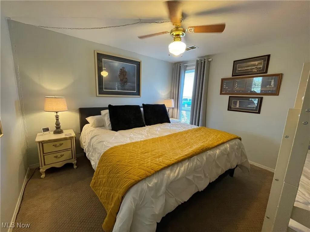 Carpeted bedroom with ceiling fan, baseboards, and visible vents