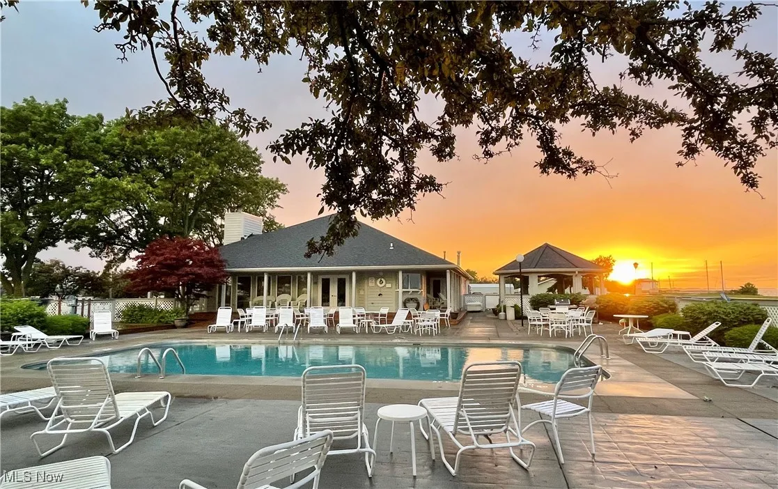 Pool at dusk featuring fence, french doors, a community pool, a patio, and a gazebo