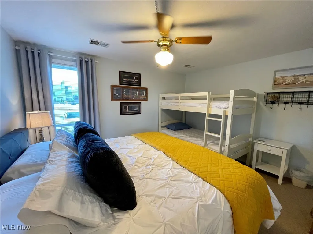 Carpeted bedroom featuring visible vents and ceiling fan