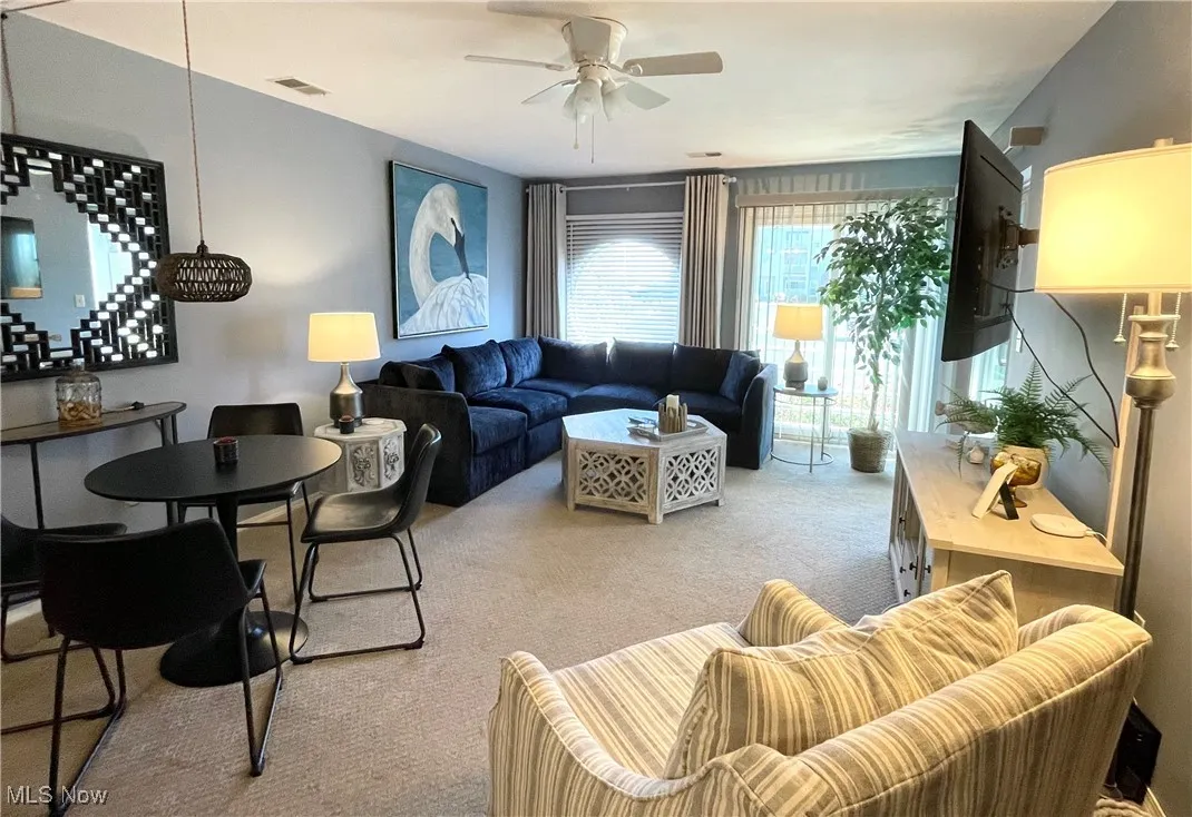 Carpeted living area with visible vents and ceiling fan