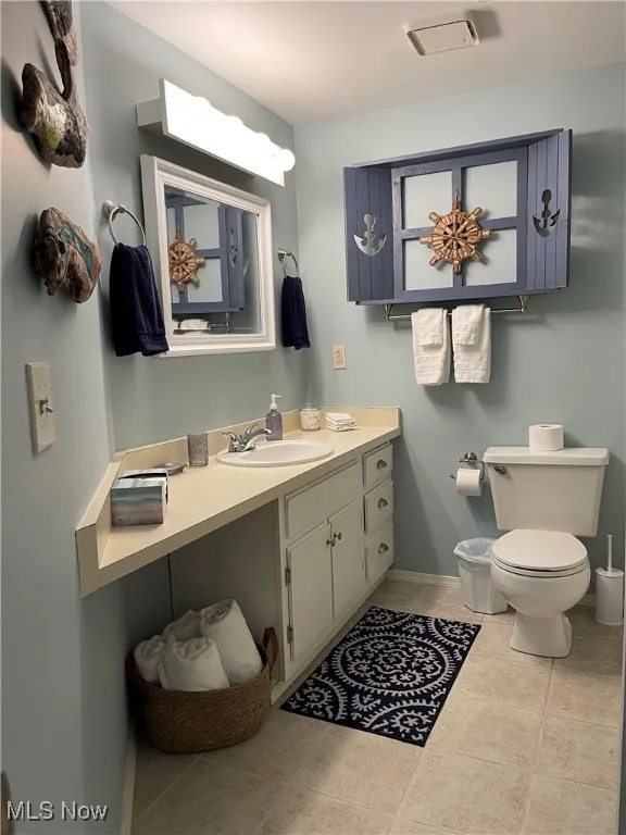 Bathroom featuring toilet, visible vents, baseboards, tile patterned flooring, and vanity