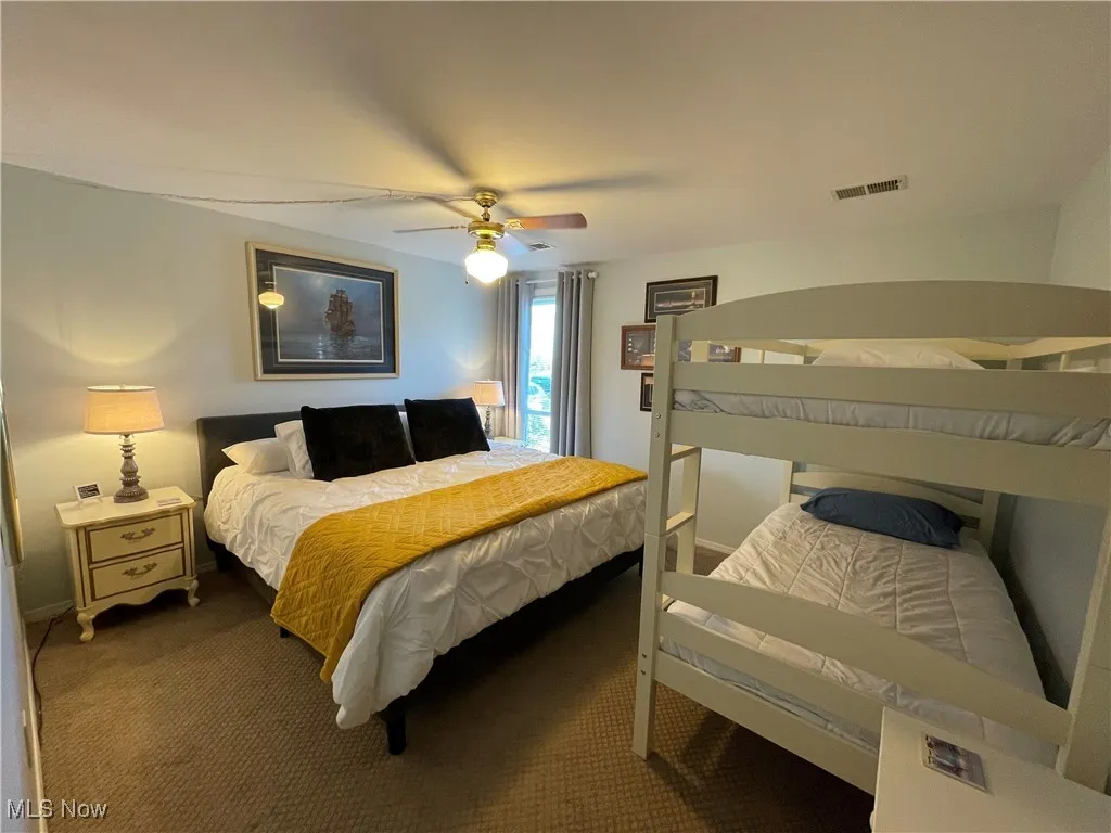 Carpeted bedroom featuring ceiling fan and visible vents