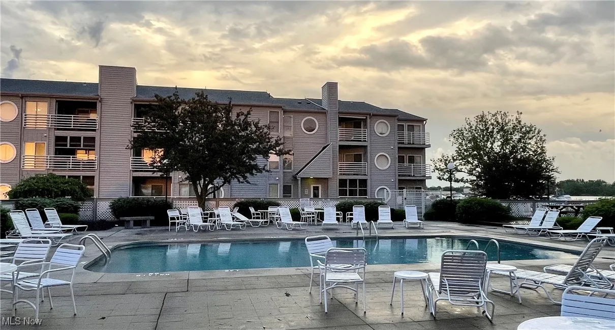 Pool at dusk with fence, a community pool, and a patio