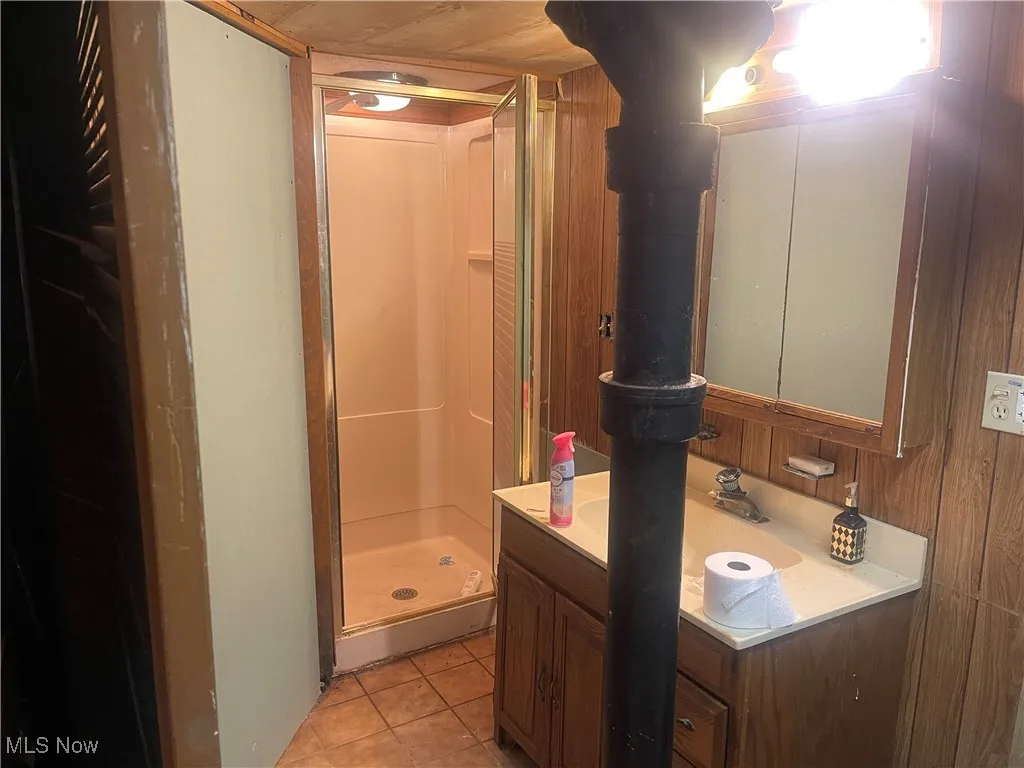 Bathroom with vanity, a shower stall, and tile patterned flooring
