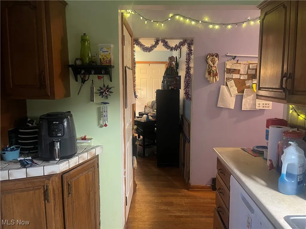 Kitchen featuring wood finished floors, tile countertops, and white dishwasher