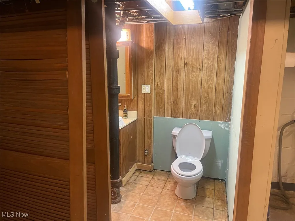Bathroom featuring wood walls, vanity, and tile patterned flooring