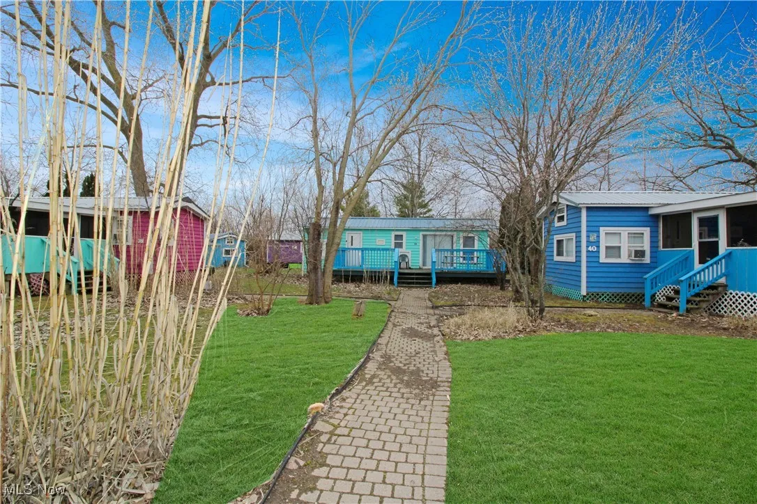 View of front of home with a wooden deck, a front yard, and metal roof