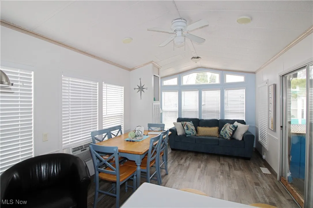 Dining area with lofted ceiling, ceiling fan, wood finished floors, and ornamental molding