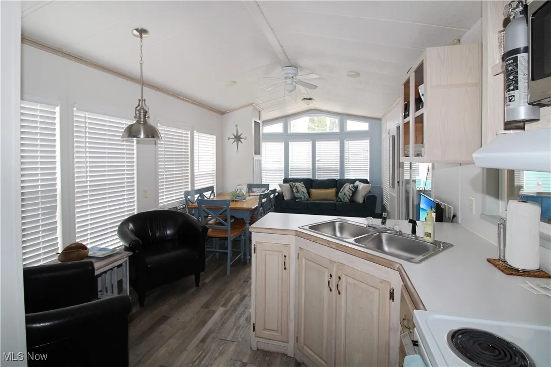 Kitchen with a peninsula, dark wood finished floors, lofted ceiling, ceiling fan, and light countertops