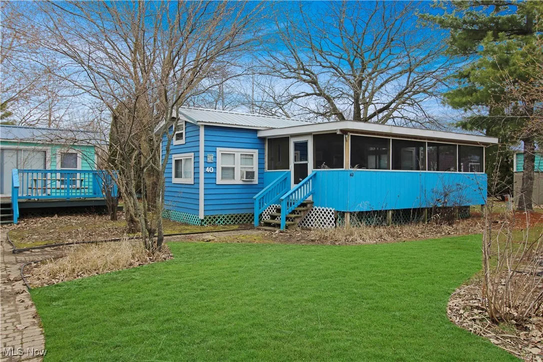 View of front of house featuring a wooden deck, a sunroom, a front lawn, and metal roof