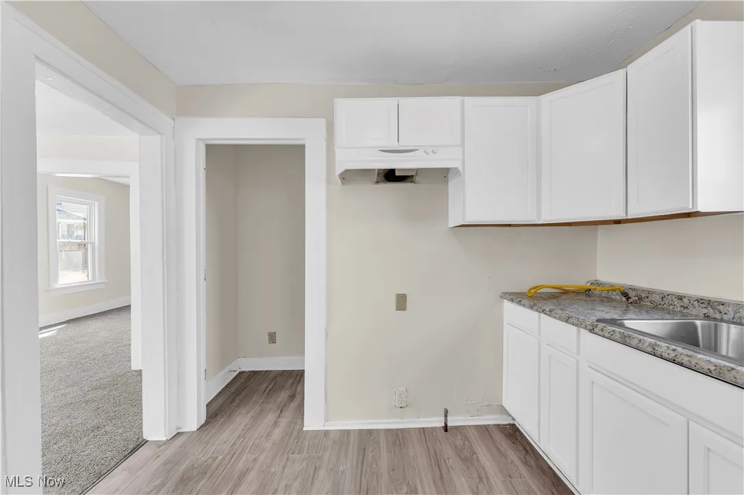 Kitchen featuring baseboards, white cabinetry, and light wood finished floors