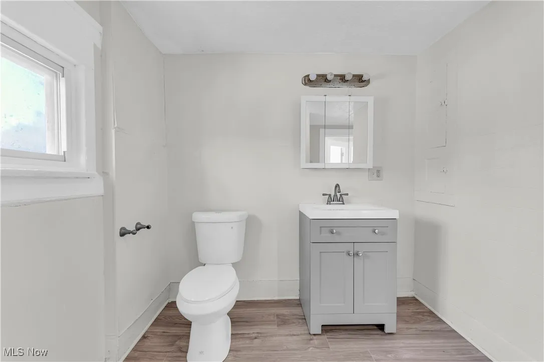 Half bathroom with wood finished floors, vanity, and toilet