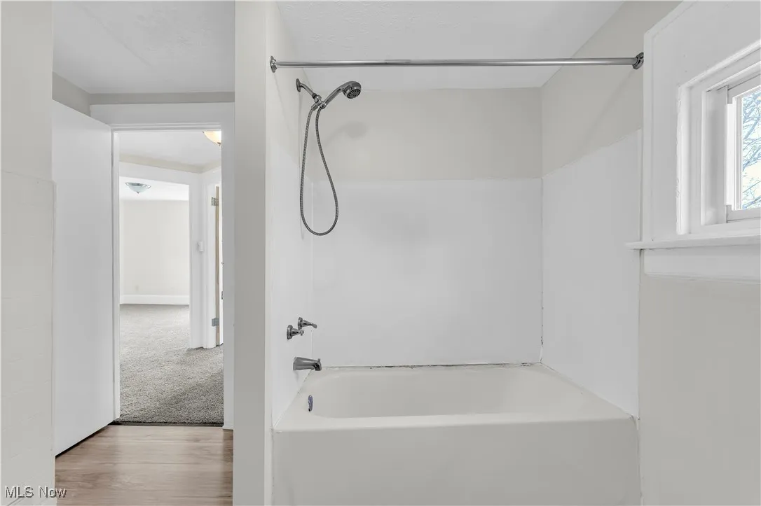Bathroom with wood finished floors and shower / tub combination