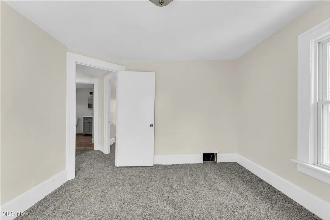 Carpeted empty room featuring baseboards, visible vents, and plenty of natural light