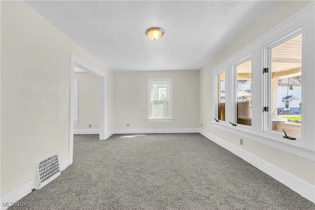 Carpeted spare room with baseboards, a textured ceiling, and visible vents