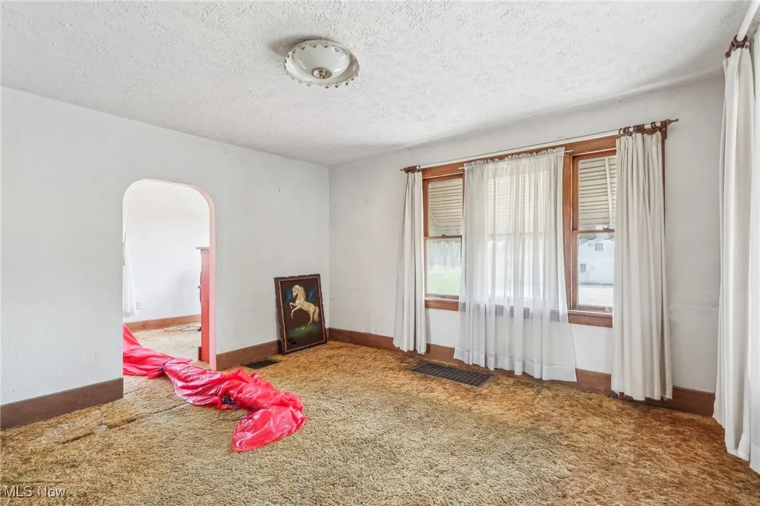 Rec room with arched walkways, carpet floors, a textured ceiling, and visible vents